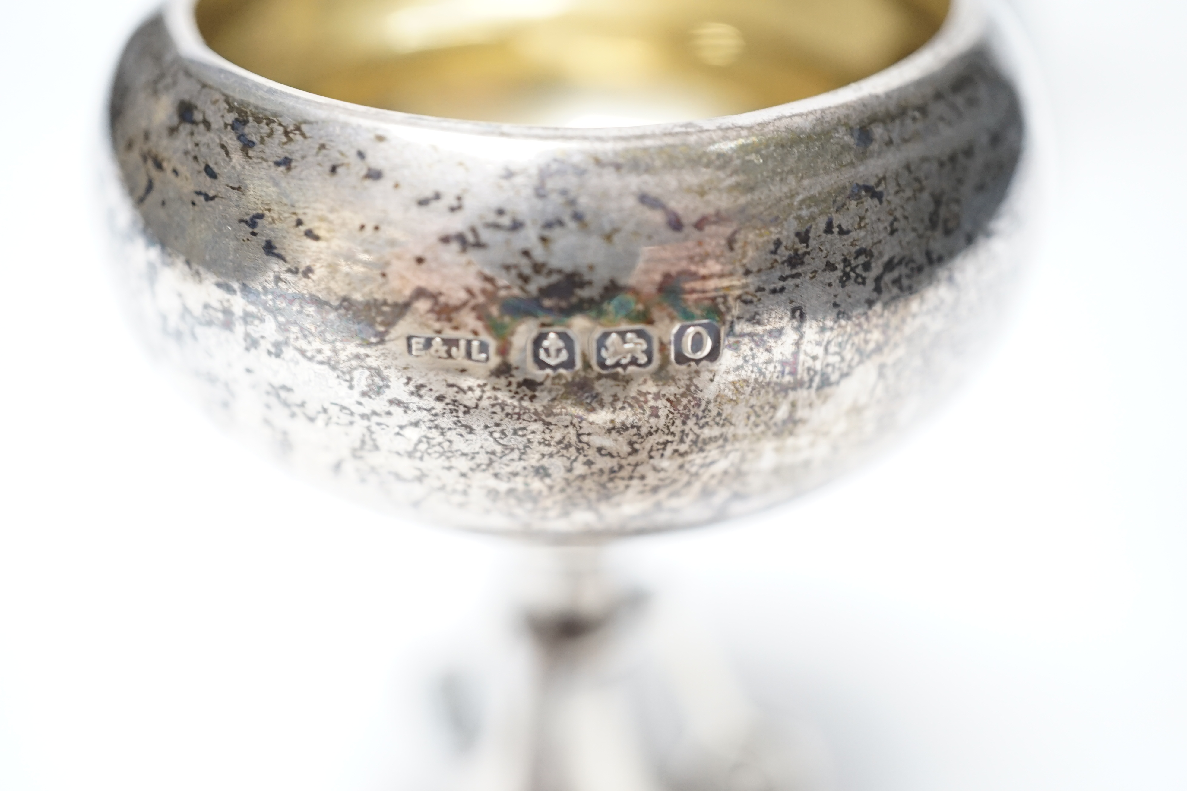 A set of three small George V silver tennis related trophy cups, with racket supports and engraved inscriptions, E & J Leek, 92mm, two with plinth bases.
